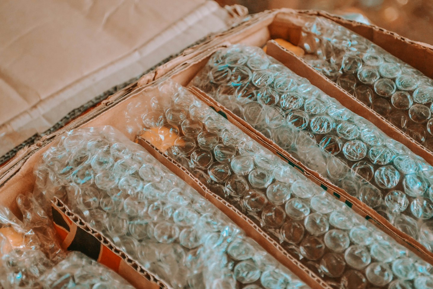 Cylindrical items wrapped in bubble wrap inside a cardboard box.