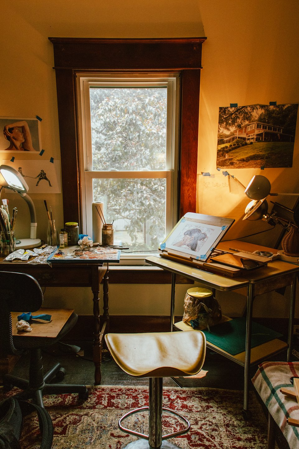 Artist's studio with a cluttered desk and easel on a drafting table.