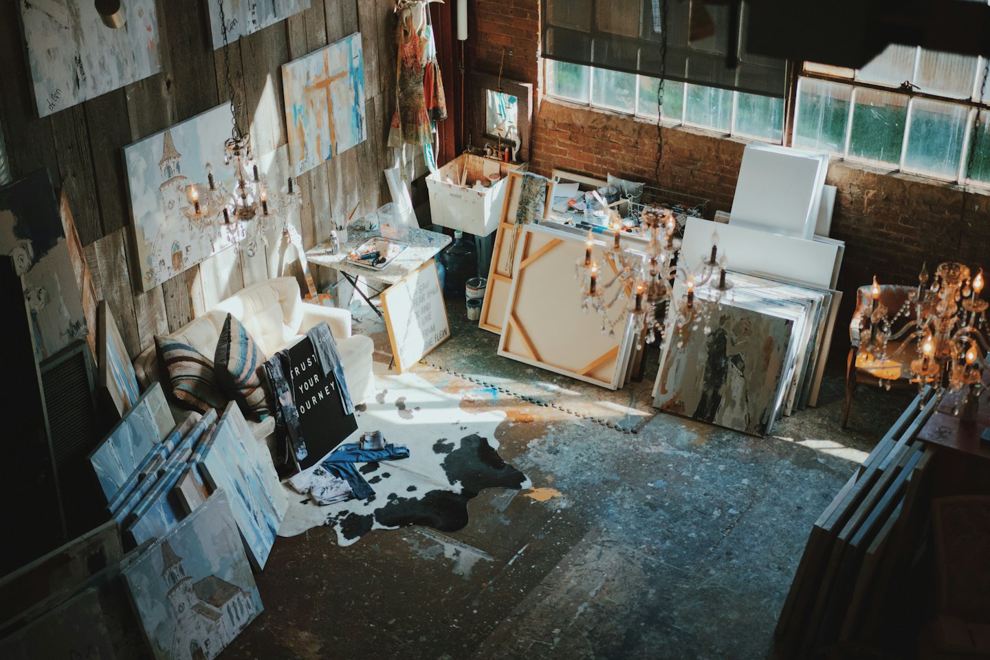 Artist studio with scattered canvases and supplies on the floor.